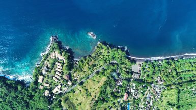 Arial view of area where lodge is located with green areas and blue sea.