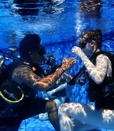 Volunteer learning diving techniques from teacher in pool