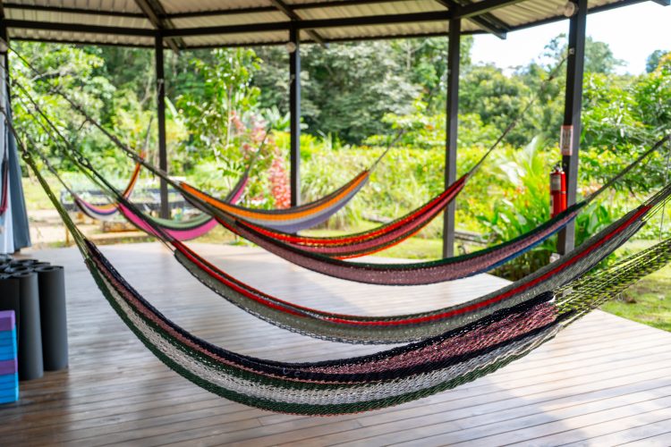 Seven hammocks hanging next to each other on open platform