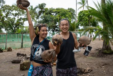 Volunteers smiling while holding coconuts in their hands
