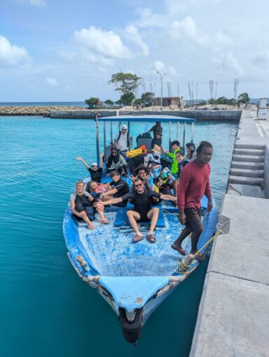 Volunteers and staff sitting on boat by harbour front