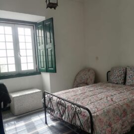 Double bed in room with large open windows bringing in light