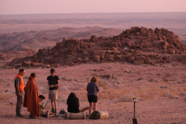 Volunteer group sitting together looking over the desert landscape turning darker