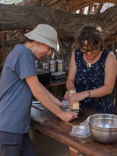 Two volunteers grinding cheese for dinner