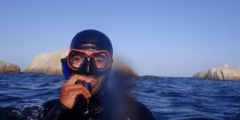 Volunteer diver in diving suit just above the surface of the water