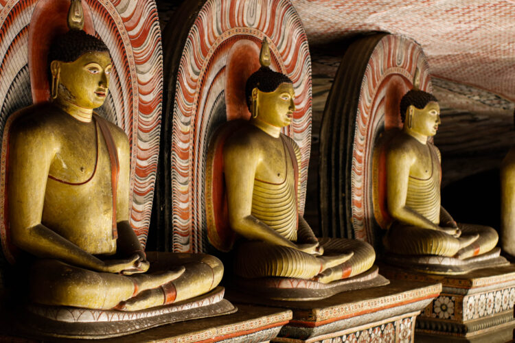 Three golden buddhas in sitting position next to each other