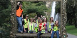 Volunteer group standing behind a large picture frame with a waterfall in the background