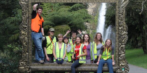 Volunteer group standing behind a large picture frame with a waterfall in the background