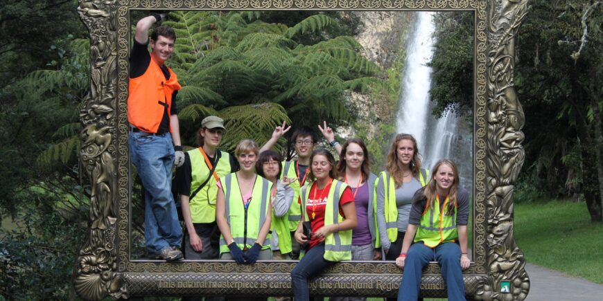 Volunteer group standing behind a large picture frame with a waterfall in the background