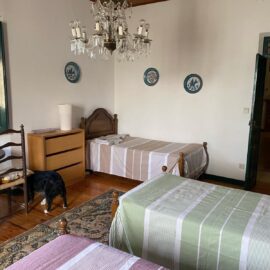 Three single beds in a room. One standng next to a drawer in the corner of the room.