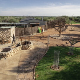 View of wildlife sanctuary lodge buildings made of stone with green grass in front.