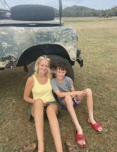 Woman sitting next to boy in front of a car