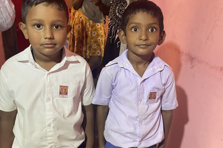 Two young boys with white shirts standing next to each other